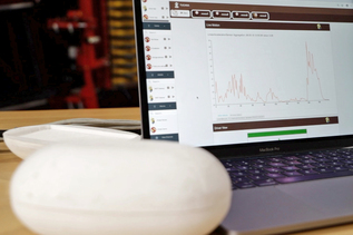 Dieses Bild zeigt den Prototyp der nPotato. Er wurde mit Kartoffelrodern des Konsortialpartners Grimme erprobt. Im Hintergrund ist das von ihr aufgezeichnete Erschütterungsprofil auf einem Laptop zu sehen.