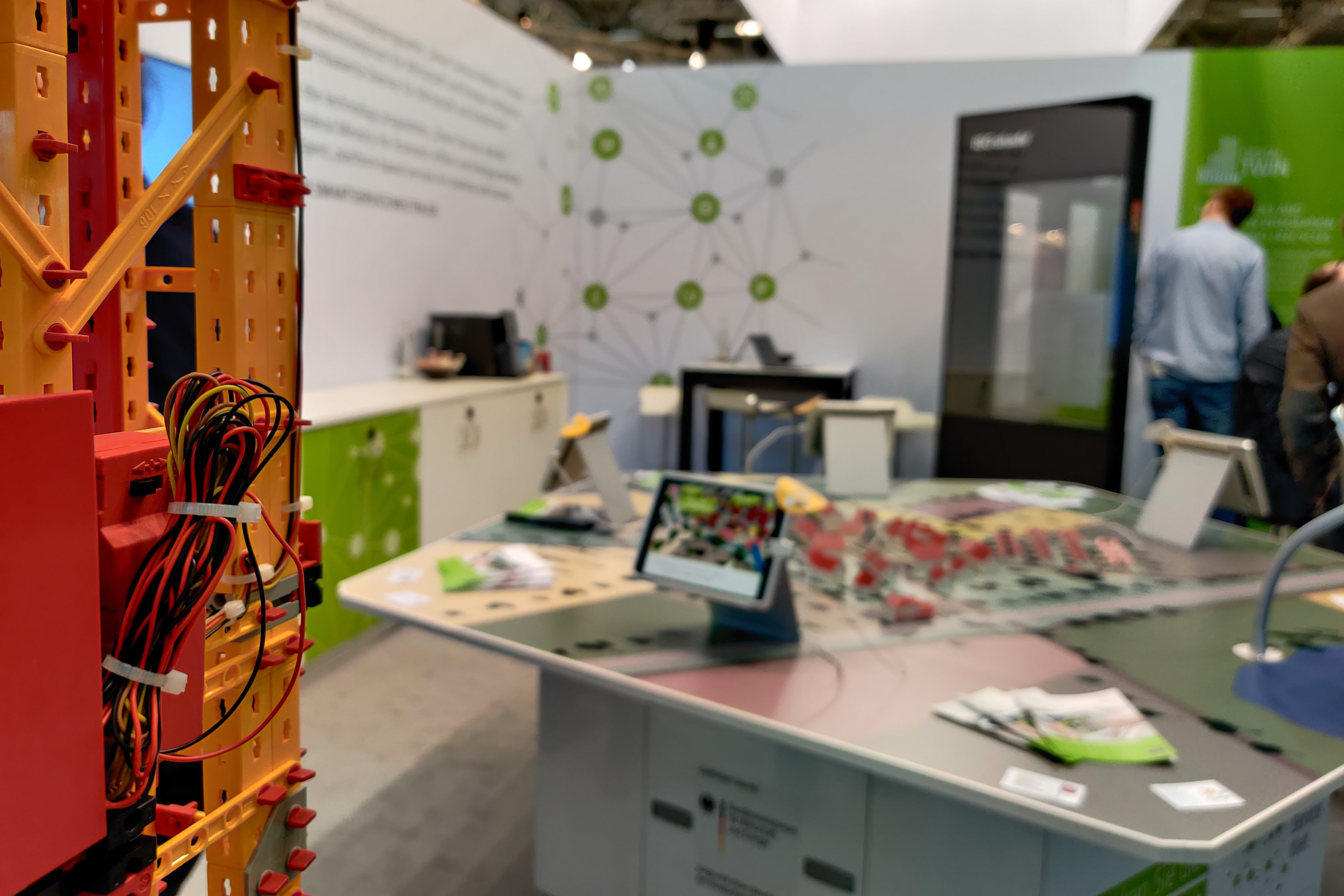 Dieses Bild zeigt im Vordergrund das Aufzugmodell von BIMSWARM und im Hintergrund den interaktiven Augmented-Reality-Tisch der Smart Service Welten.